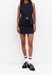 Marineblaues, gestreiftes, maßgeschneidertes Weste- und Minirock-Set mit vorderer Knopfverschluss, glattem Stoff, kombiniert mit schwarzen Schuhen und weißen Socken.