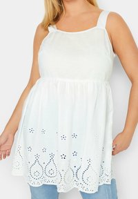 Débardeur en coton blanc avec bretelles larges, incluant un ourlet en dentelle brodée et une taille élastiquée. Confectionné dans un tissu léger et respirant.