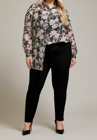 Blommig genomskinlig blus i svart och rosa, med långa ärmar och knappstängning fram. Kombinerad med svarta tajta byxor och klackar.