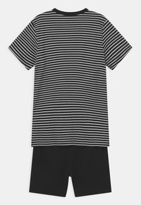 Czarny i biały pasiasty T-shirt z krótkim rękawem i okrągłym dekoltem, sparowany z jednolitymi czarnymi szortami, wykonanymi z miękkiego materiału, w luźnym fasonie.