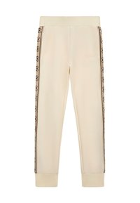Pantalons de survêtement couleur crème avec taille élastique, présentant des bandes de logo noires sur les côtés et des poignets côtelés. Fabriqués en tissu doux et lisse.