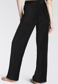 Schwarze Cordhosen mit relaxed Fit, ausgestattet mit vertikalen Rippungen, einem elastischen Bund und einem weiten Bein-Design. Keine sichtbaren Metallteile.