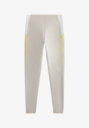 Lätta, åtsittande leggings i beige, med vita sidopaneler och gula detaljer längs sömmarna. Slät textur utan mönster.