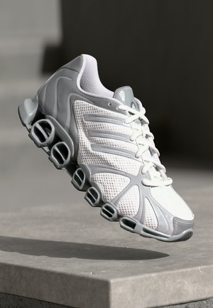 Athletic shoe with a white mesh upper and gray accents, featuring a unique sole design with circular cutouts for enhanced cushioning.