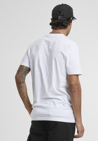 T-shirt en coton blanc à manches courtes, col rond et coupe décontractée. Présente une texture subtile et un design uni sans motifs.