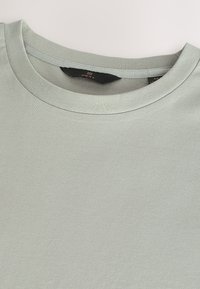 Hellgrünes Baumwoll-T-Shirt mit Rundhalsausschnitt, glatter Textur und kurzen Ärmeln. Innen am Kragen befinden sich Etiketten.