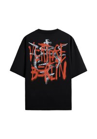Zwart oversized T-shirt met rode graffiti-stijl "HERITAGE BERLIN" tekst over een wit abstract rond ontwerp op de achterkant.