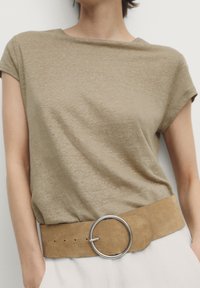 Khaki t-shirt o subtelnej teksturze, z krótkim rękawem. Połączony z szerokim, beżowym paskiem z zamszu z dużą, okrągłą srebrną klamrą.