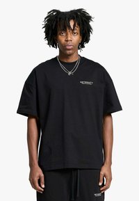 T-shirt nera oversize con maniche corte, scollo rotondo e testo con logo bianco sul petto. Realizzata in morbido tessuto di cotone.