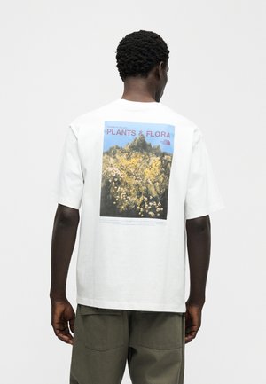 Fehér póló, amelyen a Yosemite-völgy flóráját ábrázoló grafikával és szöveggel díszített nyomat található. Rövid ujjas, laza szabású.