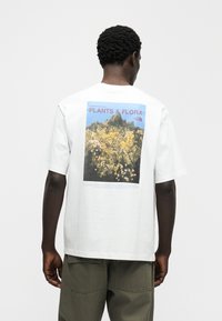 Λευκό μπλουζάκι με κοντά μανίκια και χαλαρή εφαρμογή, με γραφικό σχέδιο που απεικονίζει την χλωρίδα της κοιλάδας Yosemite και κείμενο.