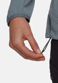 Giacca outdoor azzurra con polsini elasticizzati; tirante per la regolazione attaccato all'orlo, che mette in mostra il materiale e il design funzionale.
