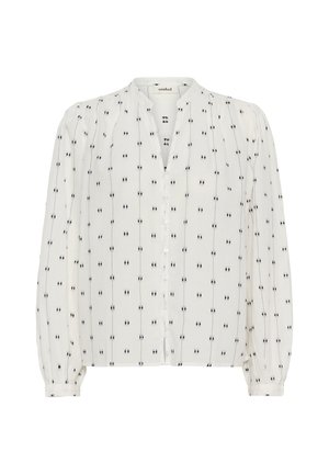 Blusa blanca con cierre de botones en la parte delantera, cuello mandarín y mangas largas abullonadas. Decorada con puntos negros dispuestos en líneas verticales.