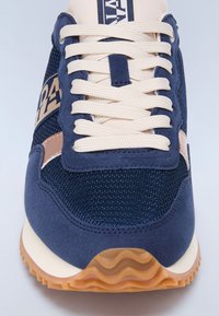 Baskets bleu marine et beige avec mesh texturé, détails en daim, lacets blancs et semelle en gomme ondulée.