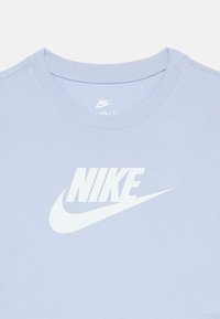 Ανοιχτό μπλε βαμβακερό t-shirt με στρογγυλή λαιμόκοψη και μεγάλο λευκό λογότυπο Nike στο μπροστινό μέρος, με απαλό ύφασμα και απλό σχέδιο.