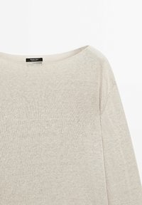 Jasno beżowy sweter z długim rękawem i szerokim dekoltem łódkowym, wykonany z miękkiego, textured materiału dzianinowego. Metka widoczna przy dekolcie.