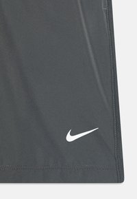 Shorts de sport gris en tissu lisse, avec un logo Nike blanc en bas à droite, et un ourlet droit et net.