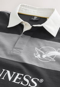 Black and gray striped polo shirt with a white collar, featuring an embroidered bird logo and "GUINNESS" text at the bottom.