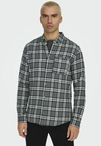 Grau und schwarzes karriertes Flanellhemd mit langen Ärmeln, Knopfleiste, einer Brusttasche und weicher Textur.