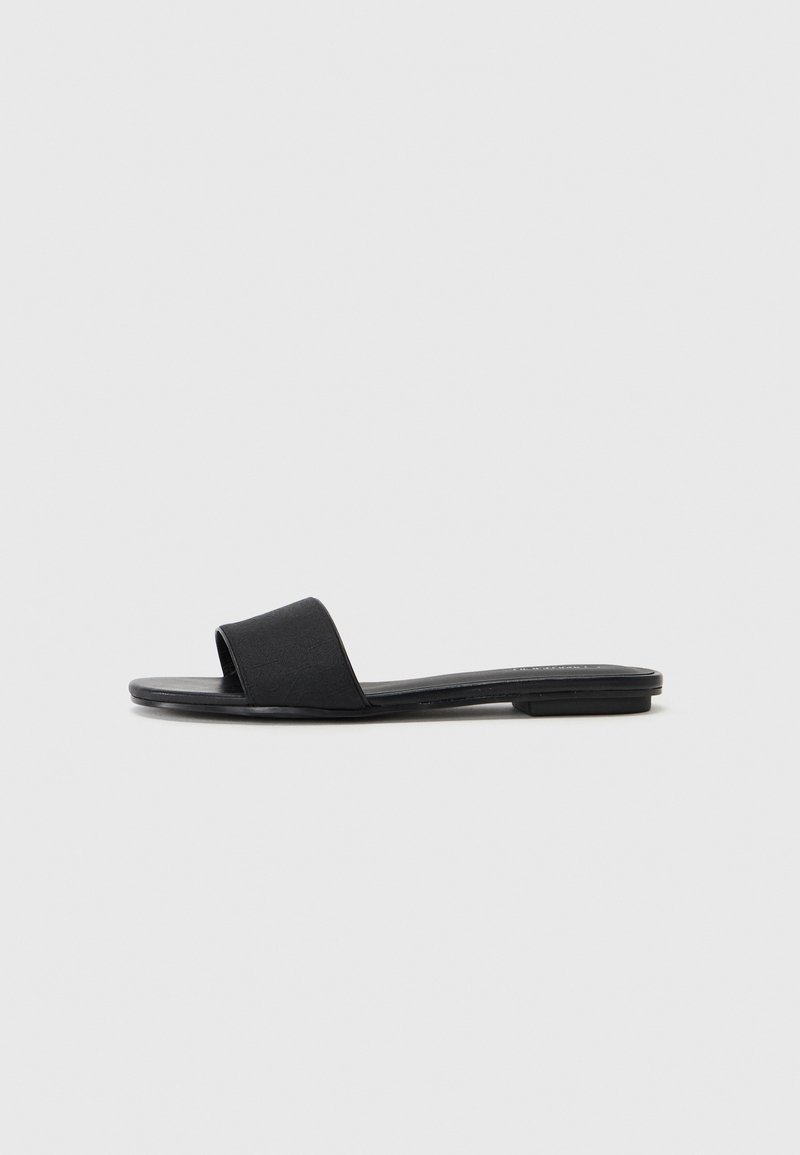 Svart slidesandal med ett brett rem, platt sula och slät yta. Minimalistisk design som passar för avslappnad användning.