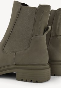 Bottes chevilles vert olive en cuir lisse et panneaux en tissu texturé, avec un bout arrondi, une semelle robuste et une languette pour un enfilage facile.