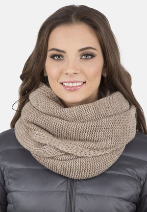 Écharpe infinity tricotée en beige doux, présentant une texture épaisse et un design en boucle, portée sur une veste grise matelassée.