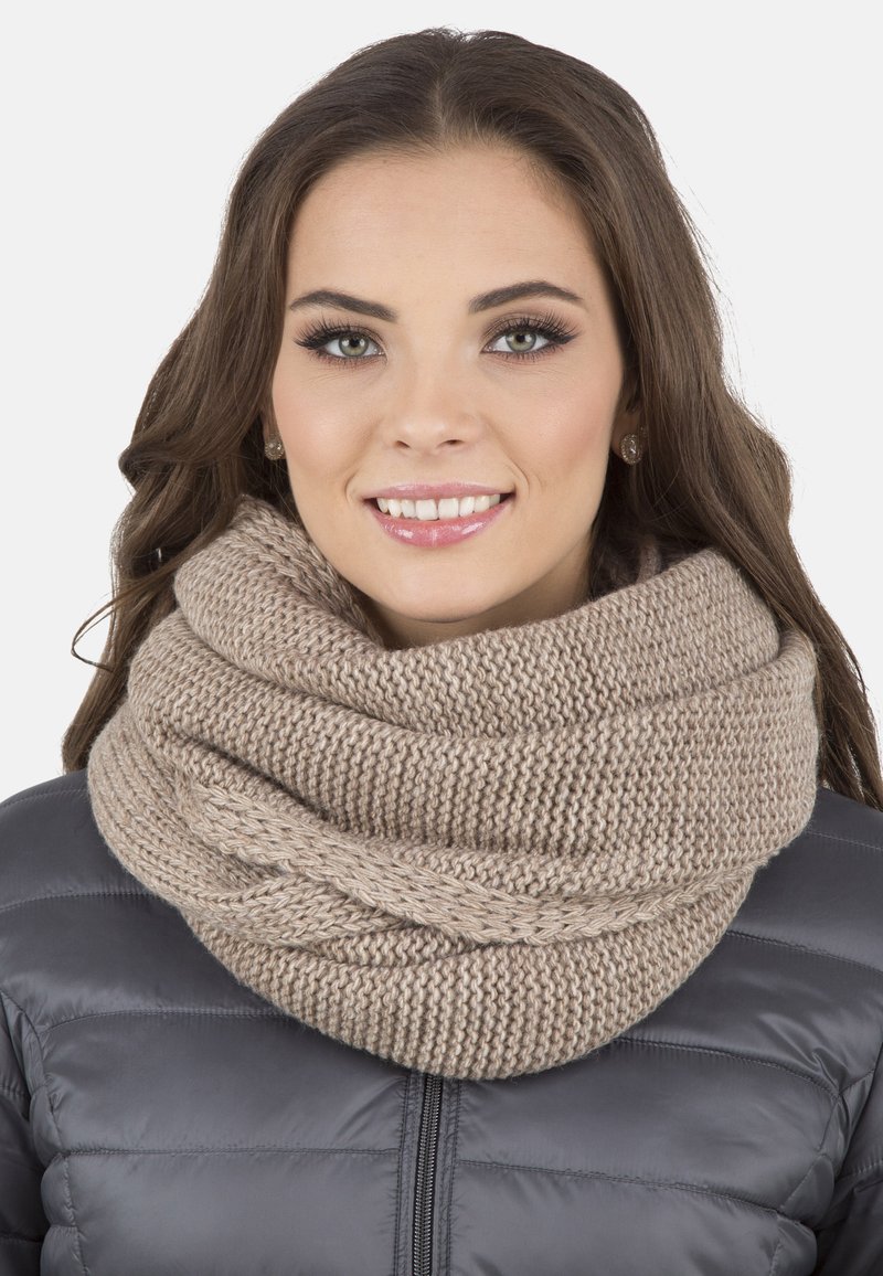 Écharpe infinity tricotée en beige doux, présentant une texture épaisse et un design en boucle, portée sur une veste grise matelassée.