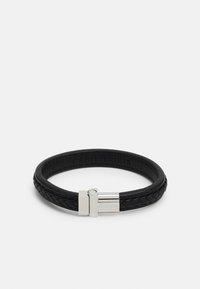 Pulseira de pele preta com padrão trançado, apresentando um fecho de metal prateado e logotipo em relevo. Textura suave, forma arredondada.
