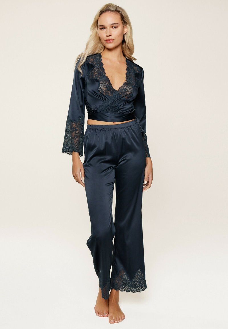Navy satijnen pyjama set met kantdetails, bestaande uit een wikkeltop met klokmouwen en broek met brede benen met gegolfde kantafwerking.