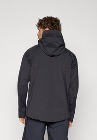 Veste noire légère avec un col montant, capuche ajustable et manches longues. Texture lisse et design minimaliste sans embellissements.