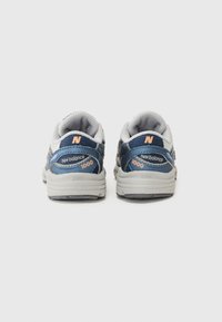 Mörkblå sneakers med grå accenter, nätmaterial och en ljusgrå sula. Har "new balance"- och "1000"-loggor i orange.