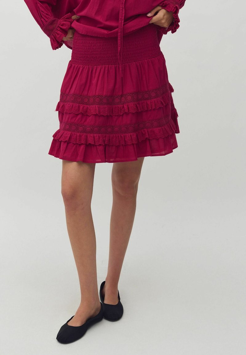 Fustă în straturi fuchsia, confecționată dintr-un material ușor, cu talie elastică și accente din dantelă, având multiple straturi volanate pentru textură.