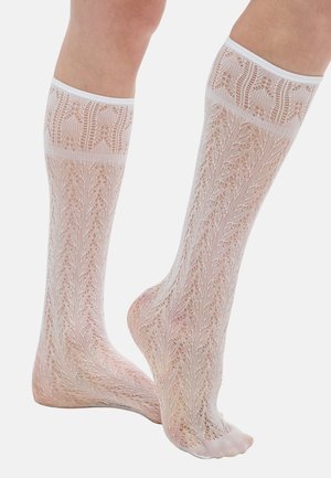 Chaussettes blanches montantes en dentelle avec un motif floral, une texture semi-transparente, et un bord côtelé ajusté. Design distinctif en forme de feuilles sur toute la surface.