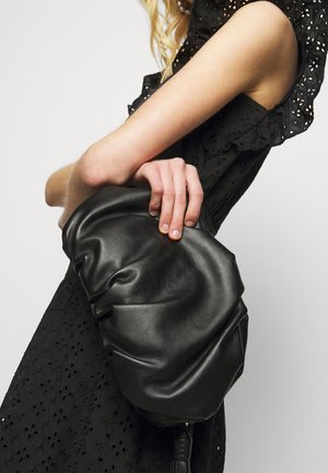 Sort lædertaske med et rynket design, der har en blød, tekstureret overflade og en kvastdetalje i bunden.