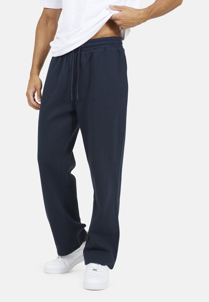 Marineblauwe, relaxte sweatpants met een elastische tailleband en trekkoord. Gemaakt van zachte stof, voorzien van zijzakken en een gladde textuur.