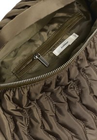 Interno trapuntato verde oliva di una giacca con tasca con zip, caratterizzato da una zip argentata e un'etichetta con la scritta "InWear" attaccata. Tessuto texture, liscio.