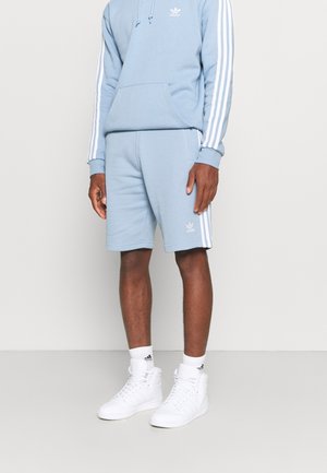 Sudadera con capucha azul claro con bolsillo frontal y rayas blancas a lo largo de las mangas, combinada con pantalones cortos a juego y zapatillas altas blancas.