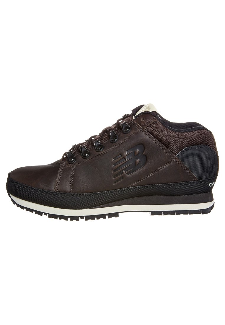 Sneaker in pelle marrone con accenti neri, caratterizzati da una finitura testurizzata, dettaglio del logo, lacci tondi e suola imbottita.