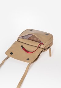 Borsa a tracolla in pelle beige con chiusura a pattina, tracolla con dettaglio rosso, interno foderato e bottoni a pressione neri. Zip su un lato.