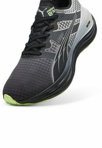 Scarpe da corsa ibride con una parte superiore in mesh nero e grigio, motivo a griglia testurizzato, design con lacci e accenti di outsole verde neon.