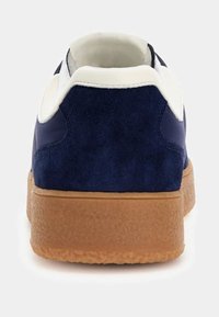 Marineblauwe sneaker met een bovenwerk van suède en stof, witte accenten, een gewatteerde kraag en een gestructureerde zool van gumrubber.