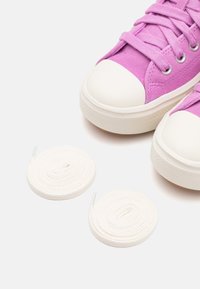Purple suede sneakers with white rubber toe caps and outsoles; includes two white laces in coiled arrangement beside the shoes.