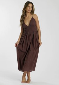 Bruine halterhals maxi-jurk met een aangesloten smock-body en een vloeiende rok. Gemaakt van een lichtgewicht stof, met een zachte textuur en een enkellange lengte.