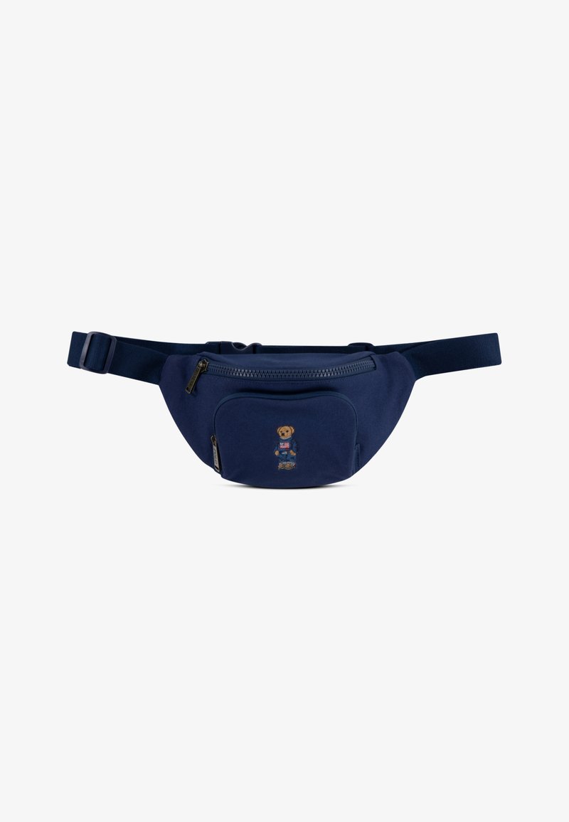 Navy fanny pack s velkým hlavním zipem. Obsahuje přední kapsu s výšivkou medvěda. Vyrobeno z odolné tkaniny, nastavitelný popruh.