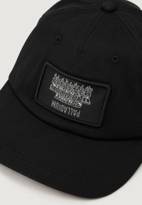 Căciulă de baseball neagră cu o pată rectangulară pe care este scris "Stranger Things" în alb și flăcări, având un material texturat și un vârf curbat.