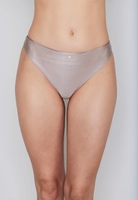 Woman's lower torso wearing shiny taupe striped bikini-style underwear with a small metallic charm at the front center.