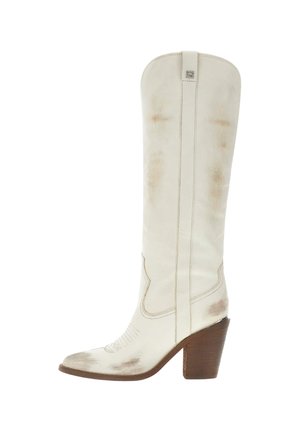 Bottes de cowboy hautes en cuir blanc avec des marques marron usées et un talon haut en bois empilé, vues de profil.