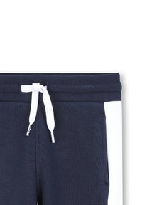 Navyblauwe sweatpants met een witte zijpaneel, elastische tailleband en witte koord met merkdetail. Zachte, rekbare stof.