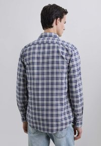 Camisa de manga larga a cuadros en azul marino y blanco, con cuello abotonado y dobladillo curvo, hecha de una ligera tela de algodón.