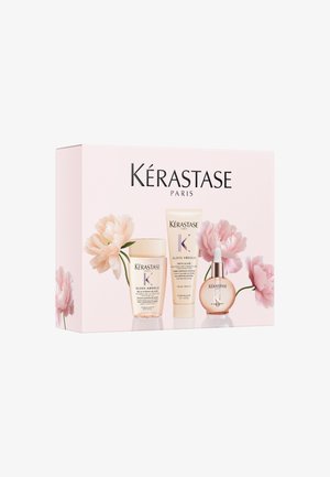 Set per la cura dei capelli Kérastase Paris Gloss Absolu con bottiglie di shampoo, crema e siero su una scatola rosa decorata con fiori rosa pallido.